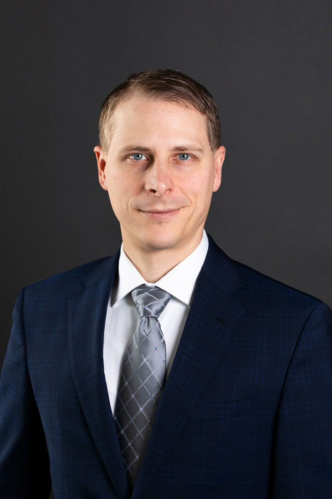 Corporate headshot of a lawyer on a grey background